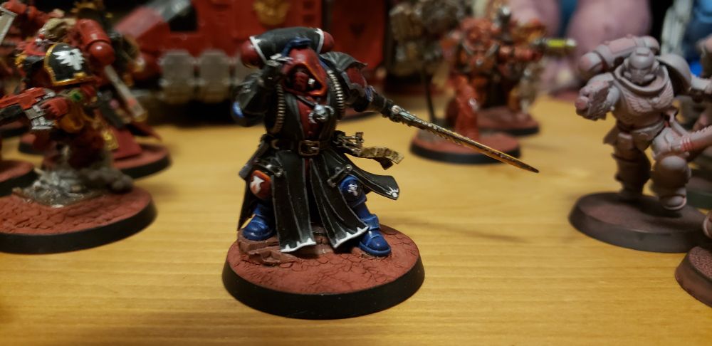 A photo of a Warhammer 40,000 miniature. This is a Librarian, a space marine who has psychic abilities, painted as a Blood Angel.