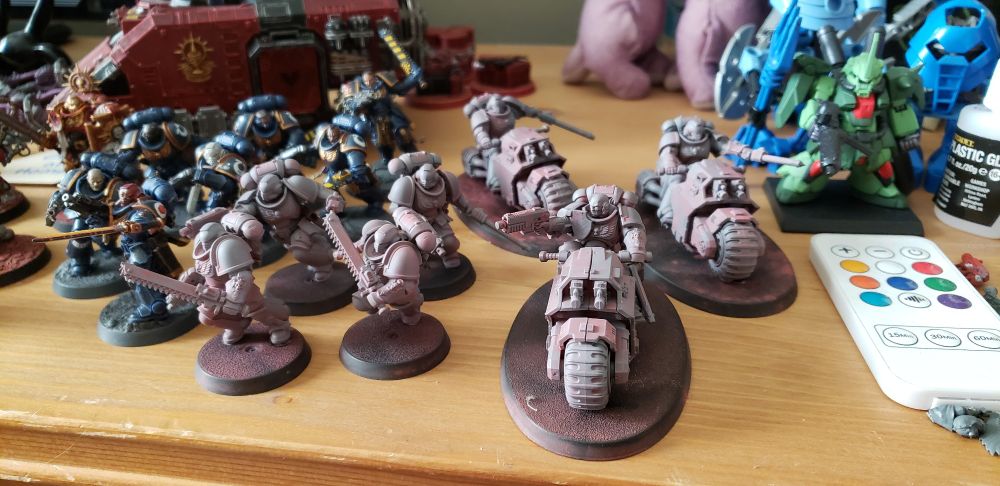 A photo of some Warhammer 40,000 miniatures. The focus is on the unpainted models up front, though there are various painted models in the background.