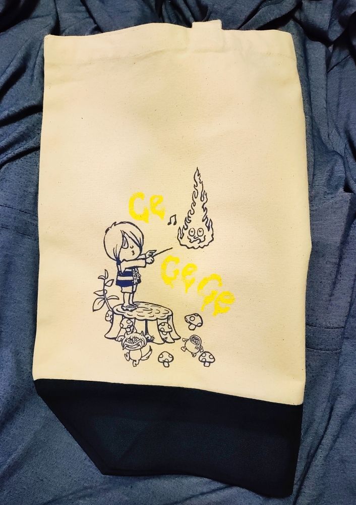 白いトートバッグ
鬼太郎が切り株の上で指揮棒を振っているイラスト
周りには釣瓶火、シーサー、達磨が居る