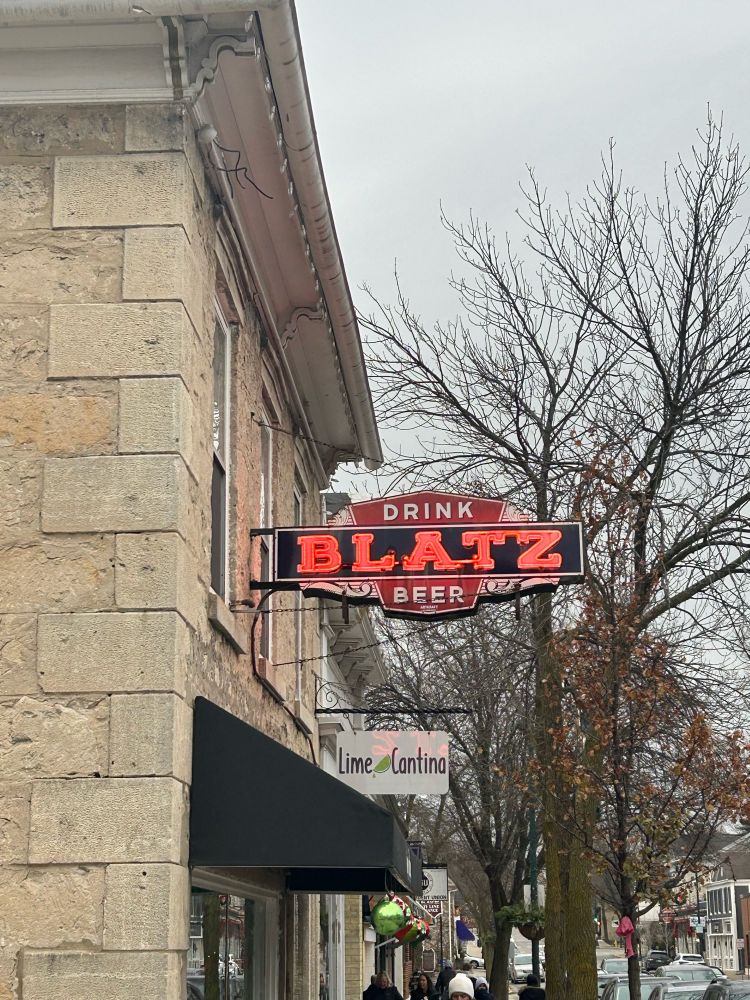 A bar sign on the side of a building that reads “drink Blatz beer” 