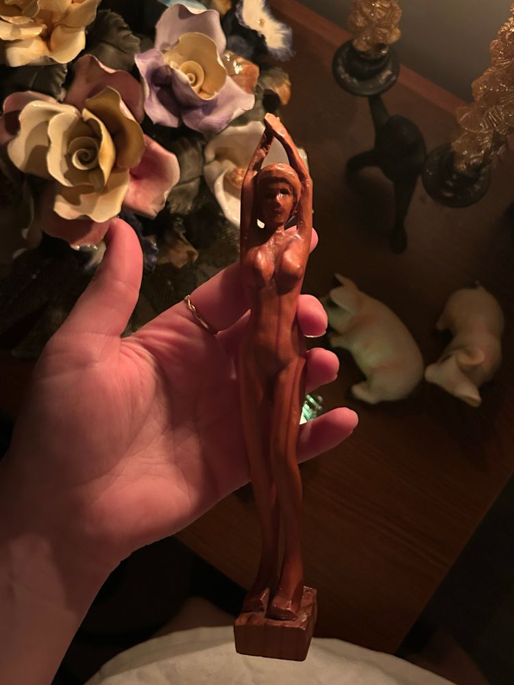A wooden carving of a feminine figure viewed from the front 