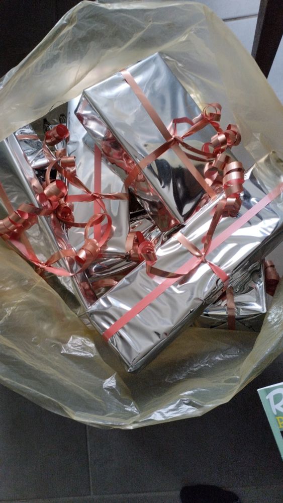 Photo d'un sac contenant plein de paquets cadeaux argentés avec bolduc rose