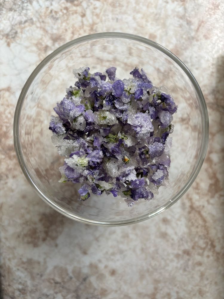 A footed glass bowl filled with candied violets
