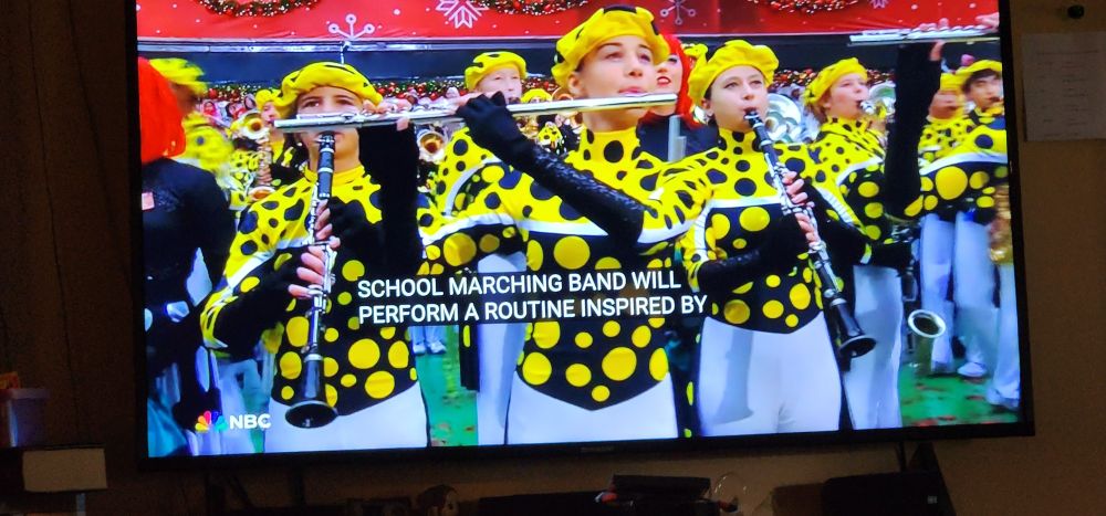 Flower Mound marching band from Texas, playing in the Macy's Thanksgiving parade in NY - wearing bold uniforms of Black and yellow polka dots with yellow berets.