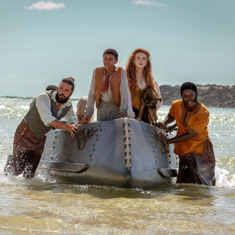 Four people stand atop a submarine, mostly submerged but in shallow water (Nemo, Blaster,Humility, and Boniface)