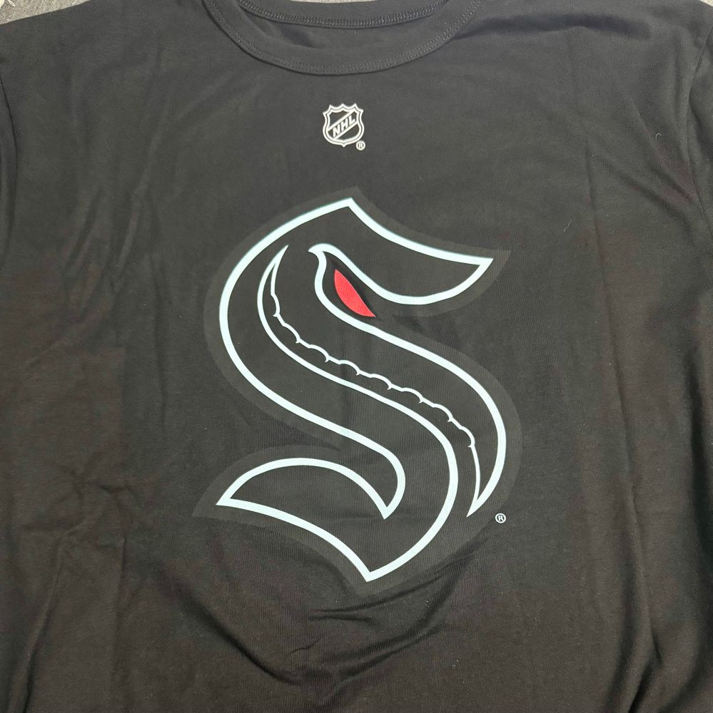 A black tee shirt with the Seattle Kraken logo on the front. 