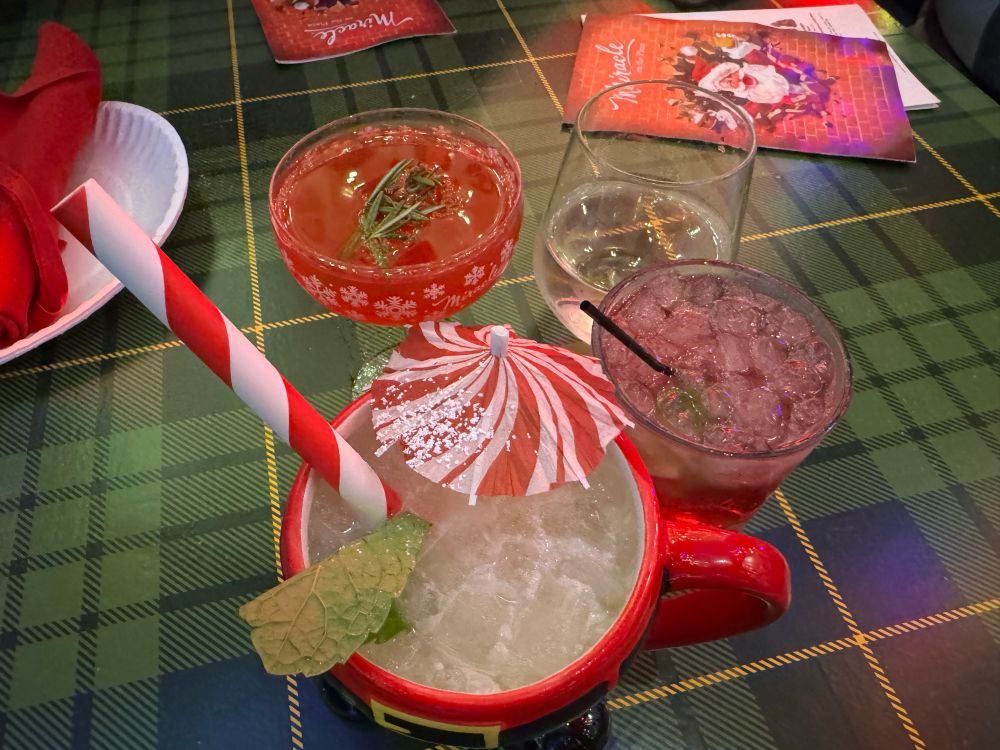 Christmas-themed drinks on a table that looks like wrapping paper. 