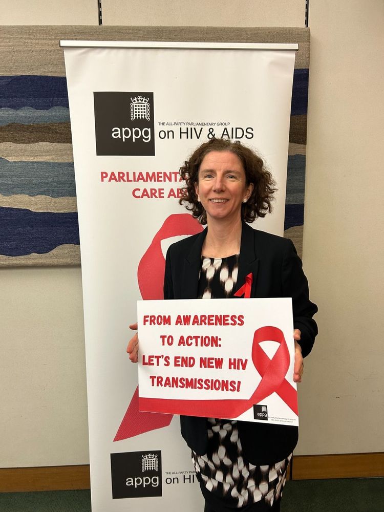 Anneliese Dodds MP stands with a sign that reads 'From Awareness to Action: Let's End New HIV Transmissions!'