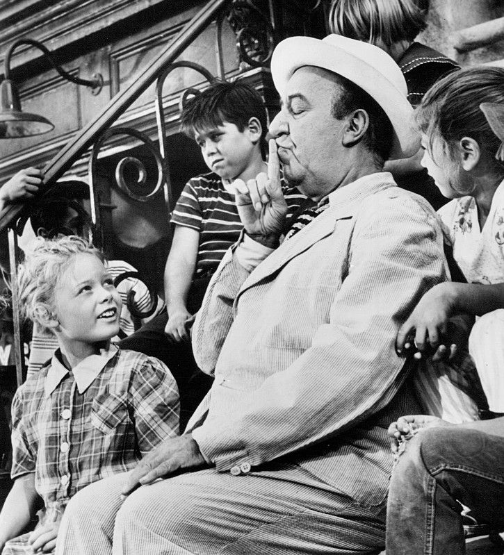 Ed Wynn as travelling salesman Lew Bookman in "One for the Angels", an episode of The Twilight Zone. He's surrounded by young children on a New York stoop, putting his finger to his lips to indicate secrecy.