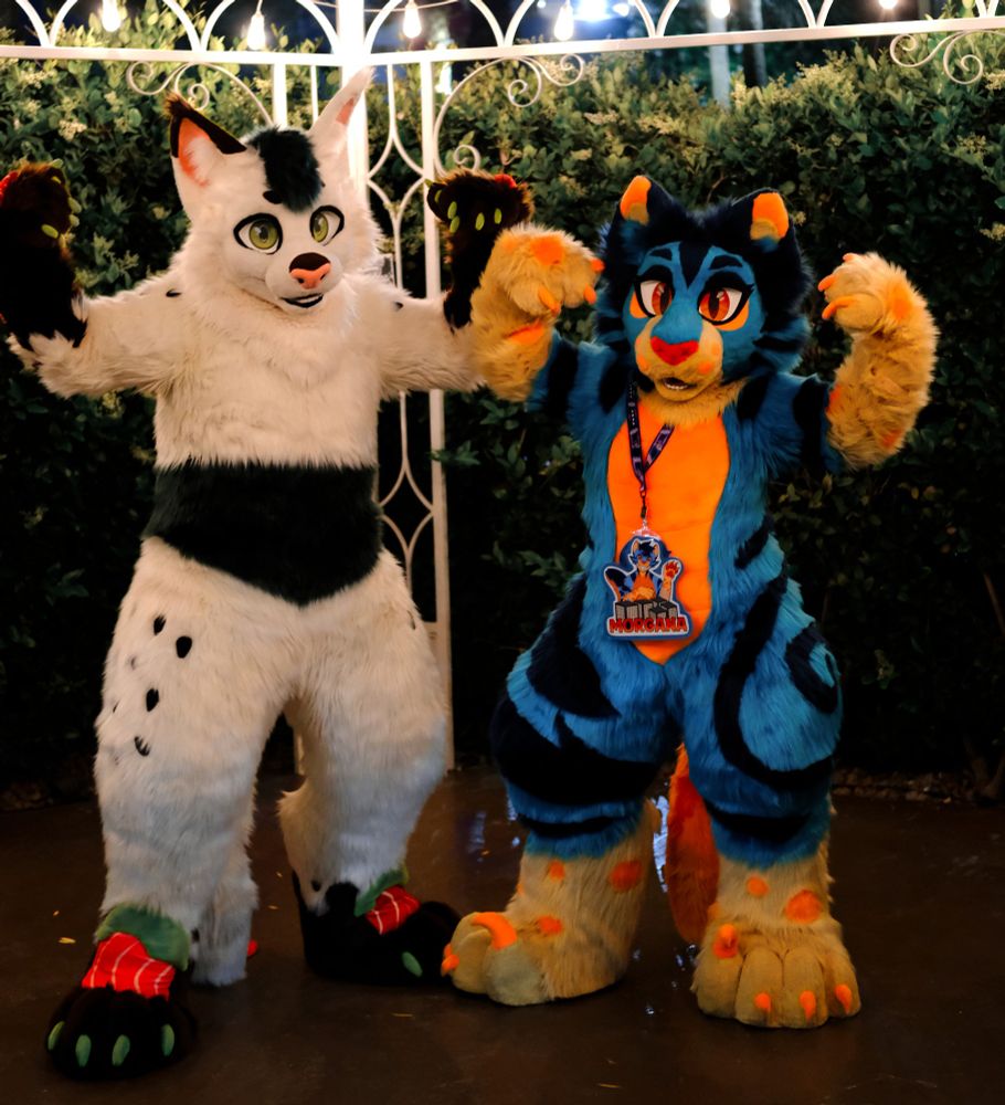Two cat fursuiters pose flexing their biceps.