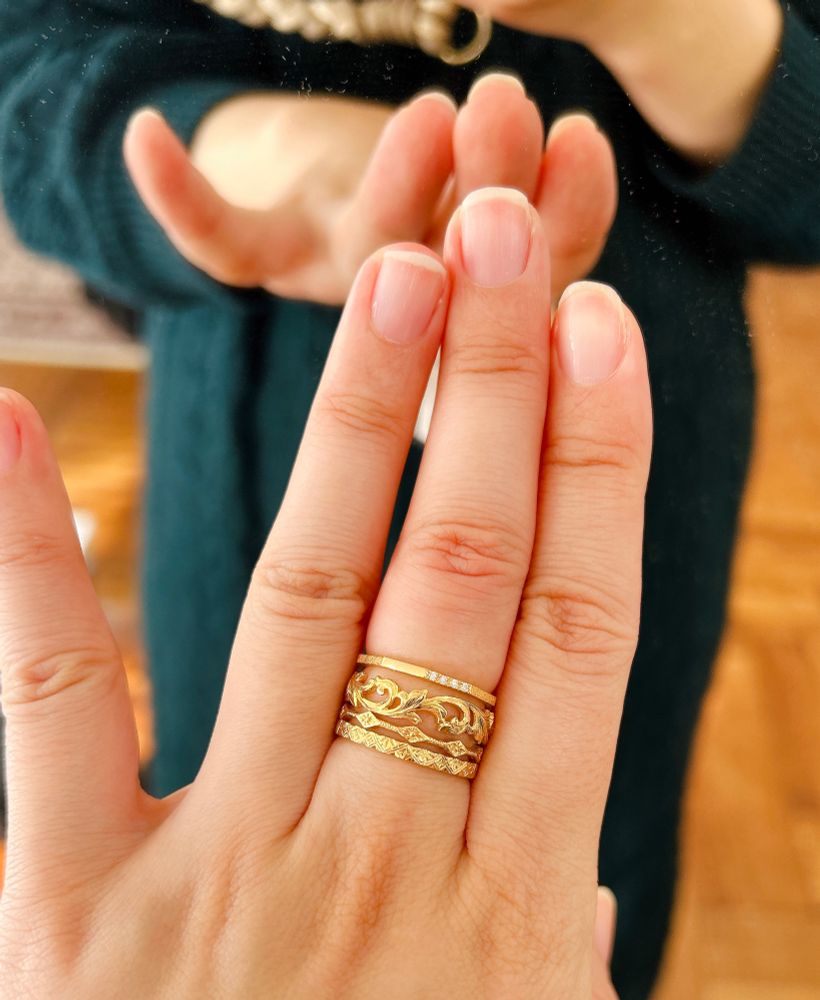 鏡に向かって手を差し出している。左手の中指に細い指輪を重ねてつけている。