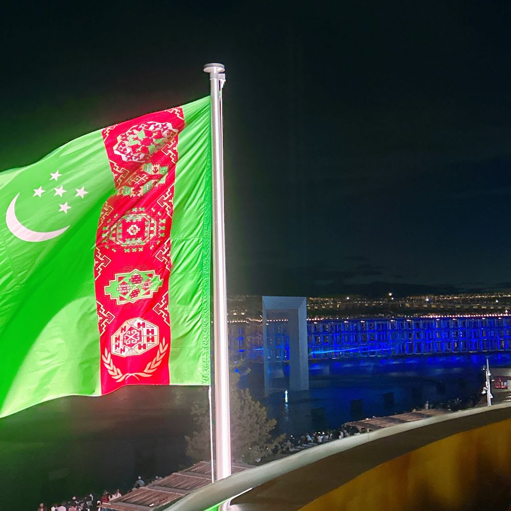 トルクメニスタンの国旗がはためくテラスから、水と光のショーが見える