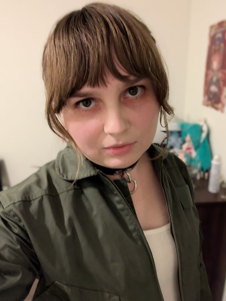 me in a flight suit and tank top looking directly at the camera