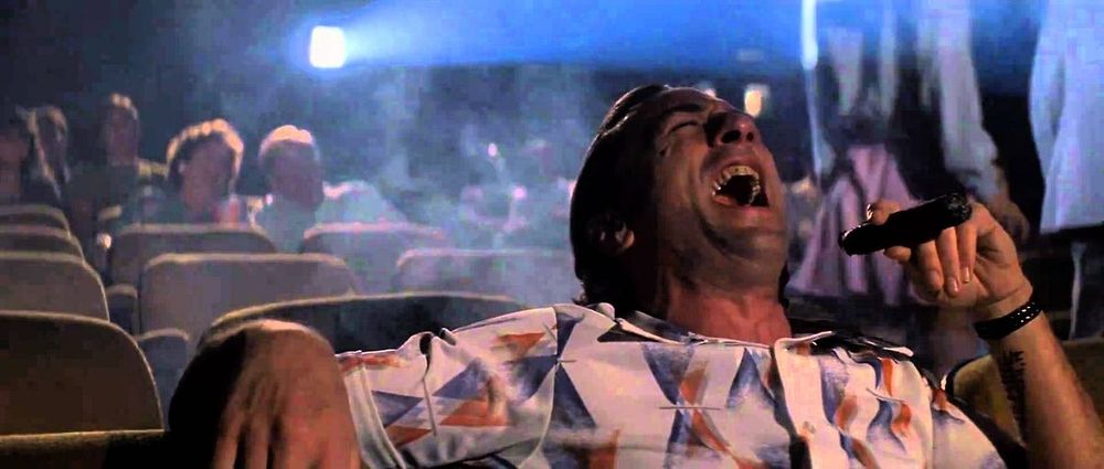 Robert Deniro in cape fear. He's a slick back haired man with a button down shirt, smoking a cigar and laughing loudly in the movie theater as the smoke swirls around the theater
