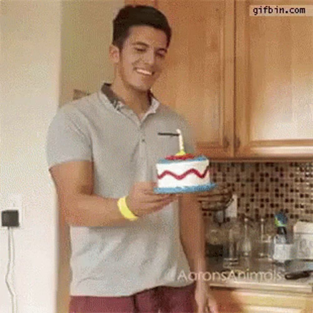 a man is holding a birthday cake with a lit candle on it .