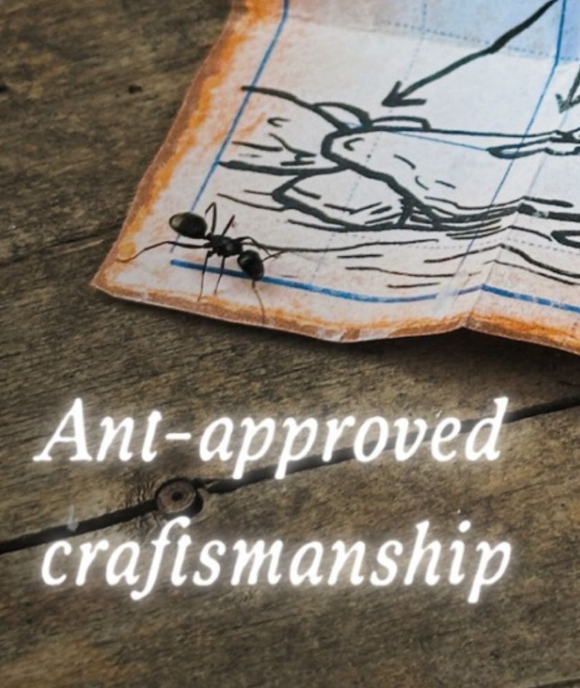 A close-up of a tiny black ant walking across the corner of miniature bridge-building plans on weathered wood. The plans hand-drawn and aged with orange-brown edges. Below, glowing white text reads: “Ant-approved craftsmanship.” The image highlights the tiny scale and whimsical detail of the handmade piece.