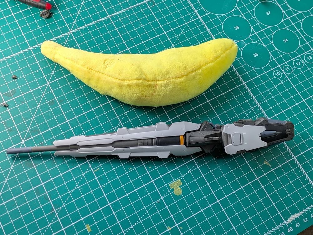 A large plastic gun, various moving parts are stowed for storage, rendering it slightly more compact. There is a banana (and probably slightly more helpful 10mm) grid for scale