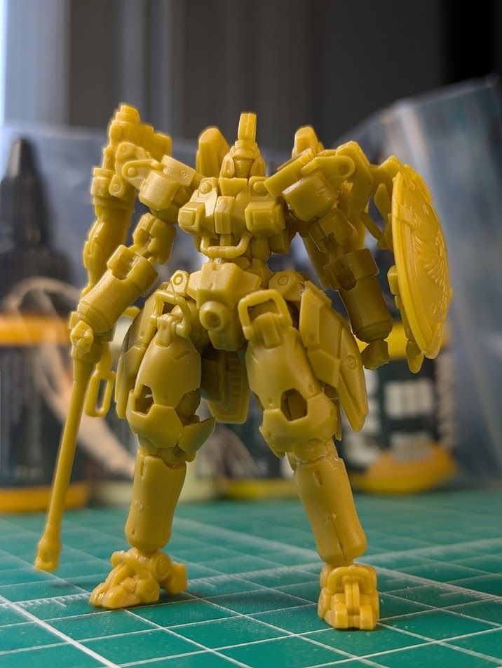 A Gundam Artifact model of the Tallgeese from Gundam Wing. Its between 50 and 60mm tall and made out of a yellow ish ABS plastic.