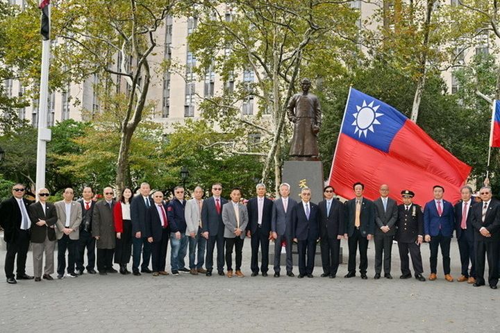 Group of people flying the Republic of China flag in front of a statue of Sun Yat-sen in New York