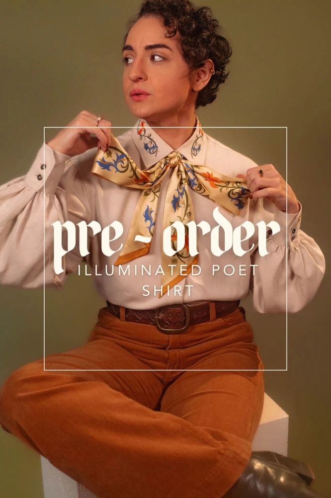 An image of the Illuminated Poet Shirt and Scriptorium Scarf, as modeled by Vic, he/they.
