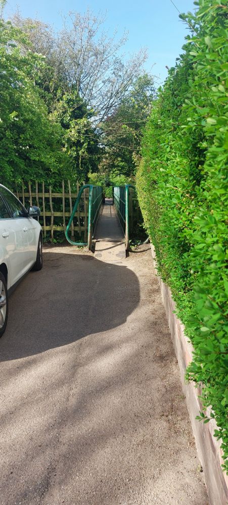 Access to the footbridge on the Mill side. You have to squeeze between the hedge and the residents parked cars.
