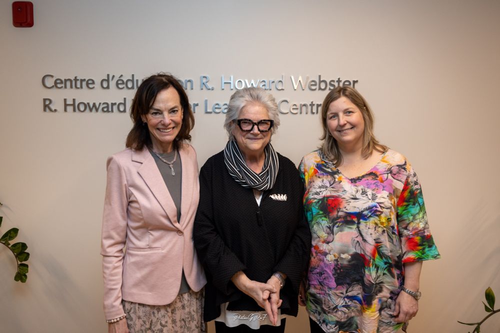 De gauche à droite : une femme aux cheveux foncés portant un blazer clair, une femme aux cheveux blancs portant une chemise foncée et une femme aux cheveux plus clairs portant un haut coloré sourient à l'appareil photo sur un fond beige.