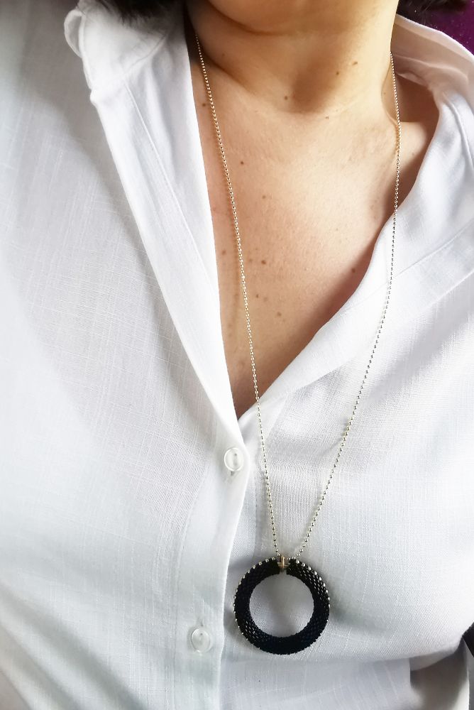 The hoop pendant necklace from previous image, worn by Robearta who is wearing a very low-cut white shirt.