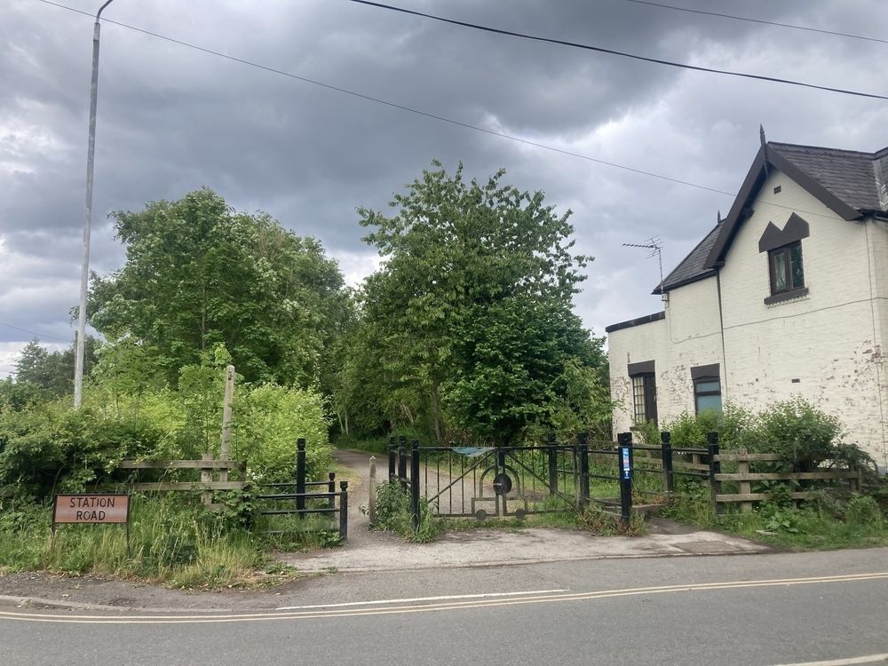 A country lane with a street sign: Station Road. The trail continues alongside a white painted cottage.