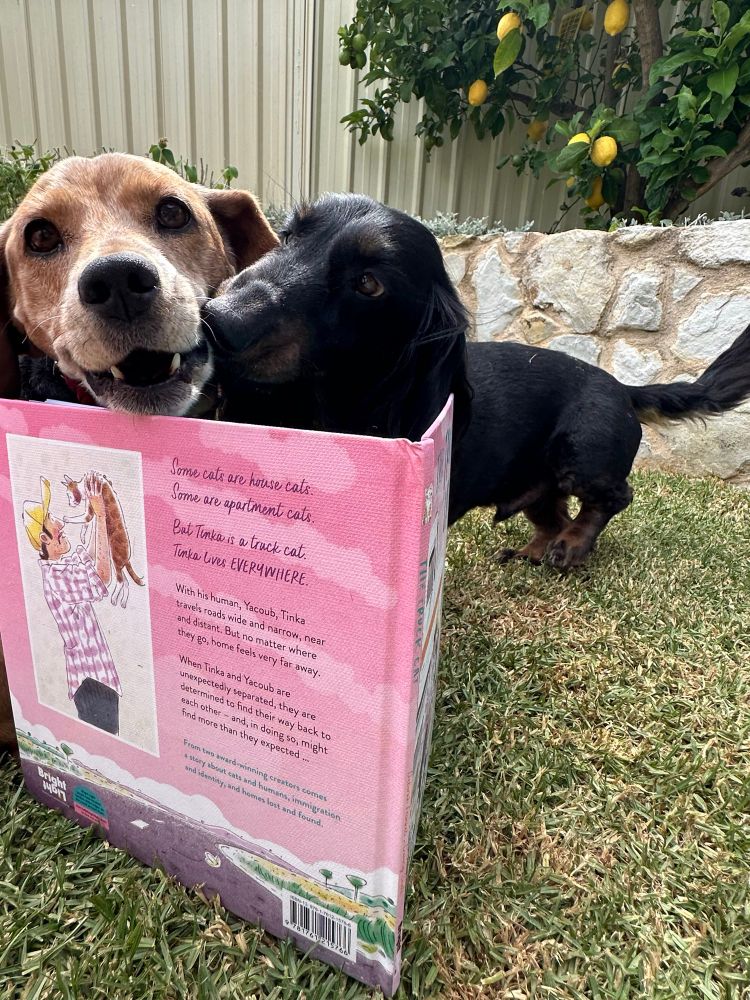 Two dogs reading the ALIA NSS book “The Truck Cat”
