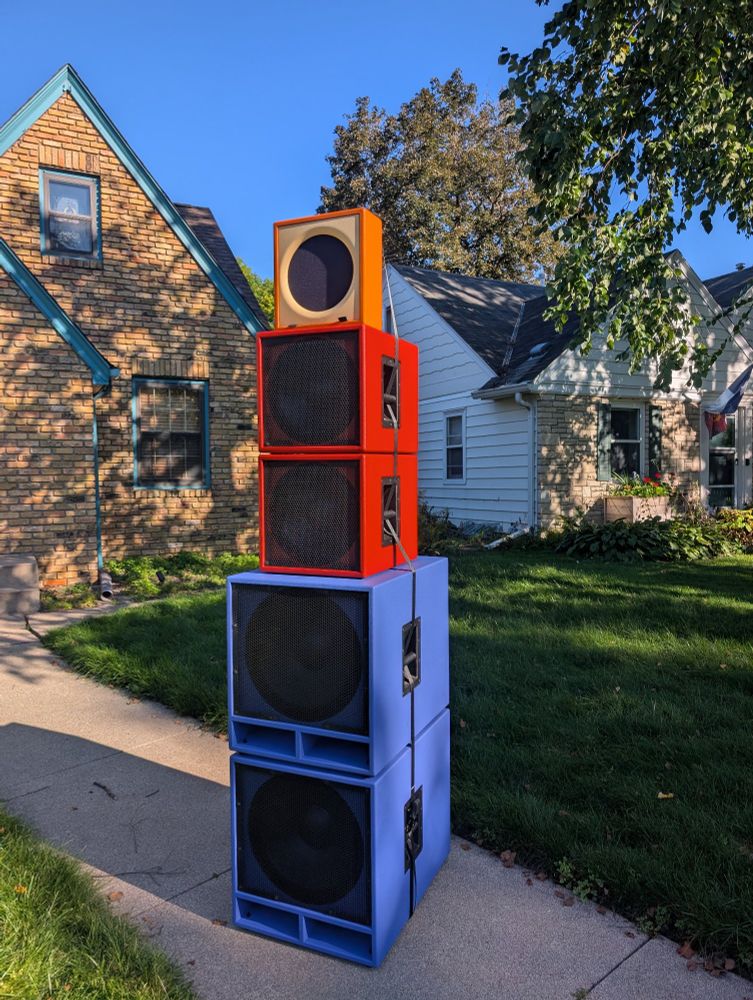 column of five speakers stacked outside on my front walk. two purple subs, two red mid subs and an orange high pack on top.