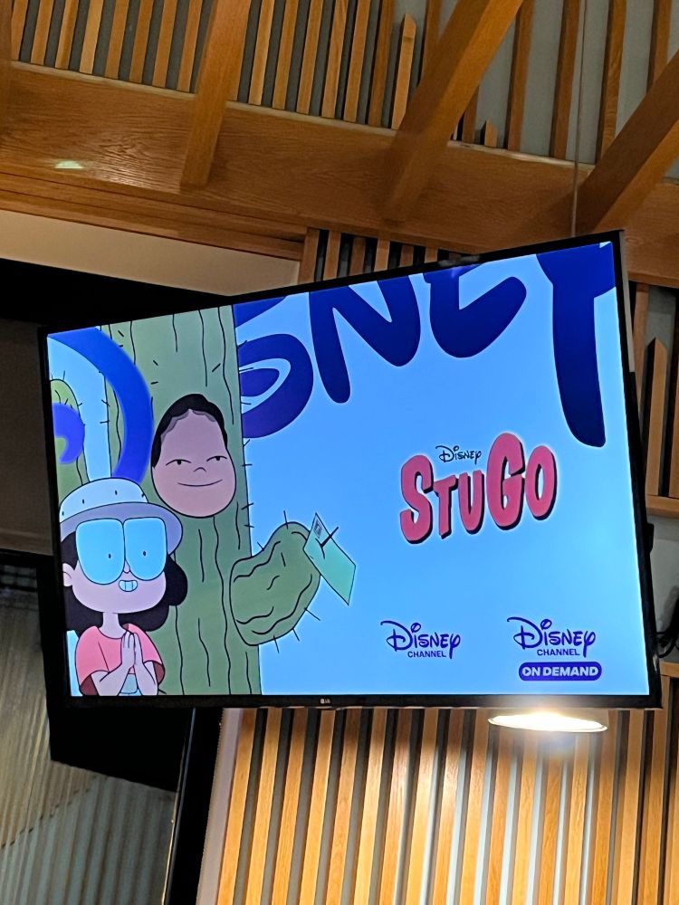 Flat screen tv at a restaurant showing the promo card of a commercial for the Disney show Stugo