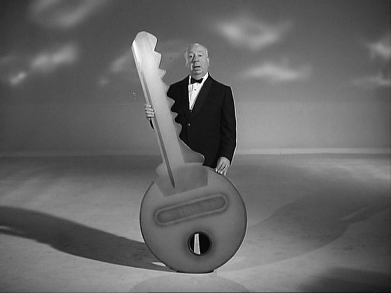 Alfred Hitchcock sostiene una llave gigante. 