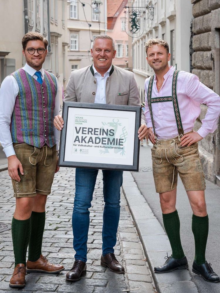 Bild zeigt 3 Männer, von denen, überspitzt gesagt, 2 wie zu einem Brauchtumsfasching gekleidet sind.