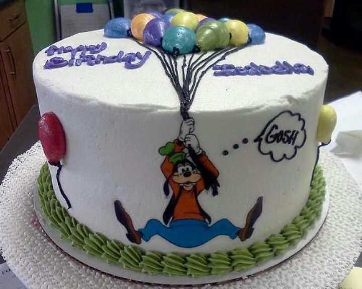 uma foto de um bolo branco com detalhes verdes no fim, simulando grama, e em cima um pateta segurando varios baloes e voando pra cima