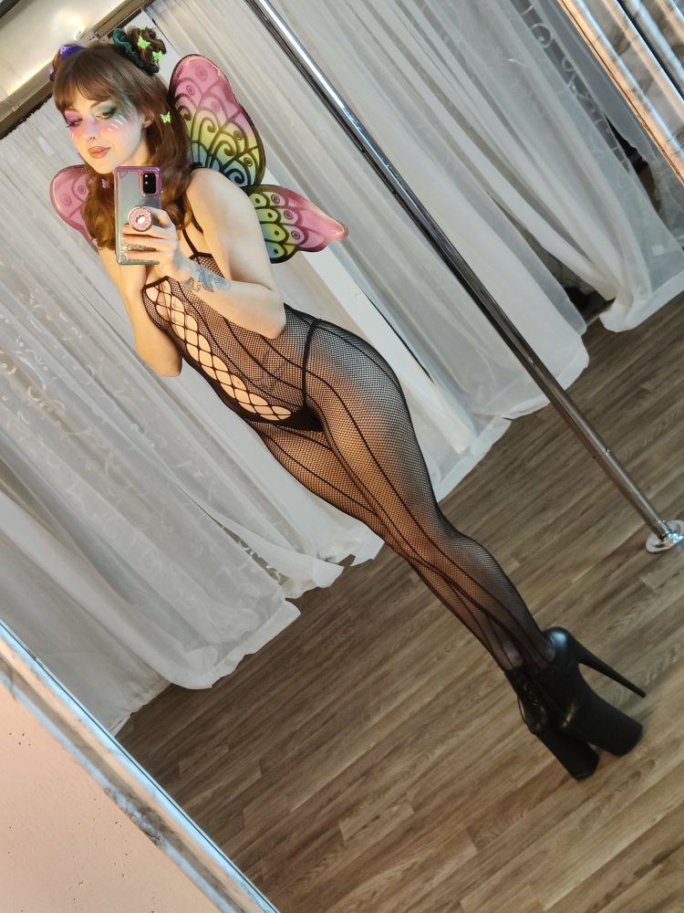 Mindy in a black mesh body suit and black high heels. 