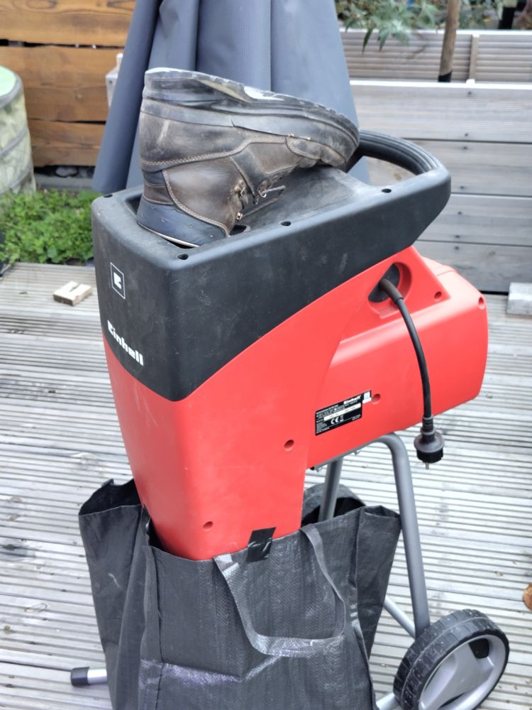Ein Gartenhäcksler, wo oben nur noch ein Schuh heraus schaut.