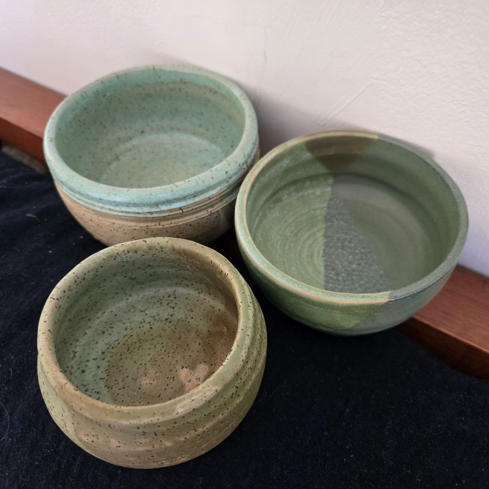 Three pottery bowls, all in shades of green. These were made with speckled clay, and the speckles show through.  It doesn't look it, but the one in back is the largest and the one in front the smallest.  