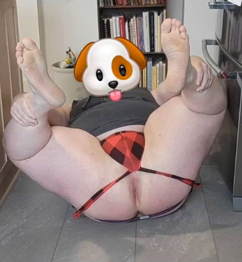 Picture of a good boy in a red plaid jockstrap, laying on the floor, feet up