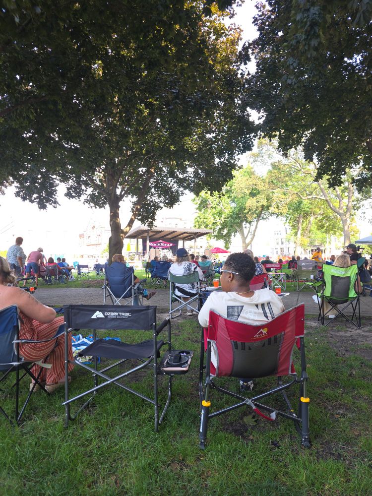 A bunch of people sit in folding chairs in front of a stage