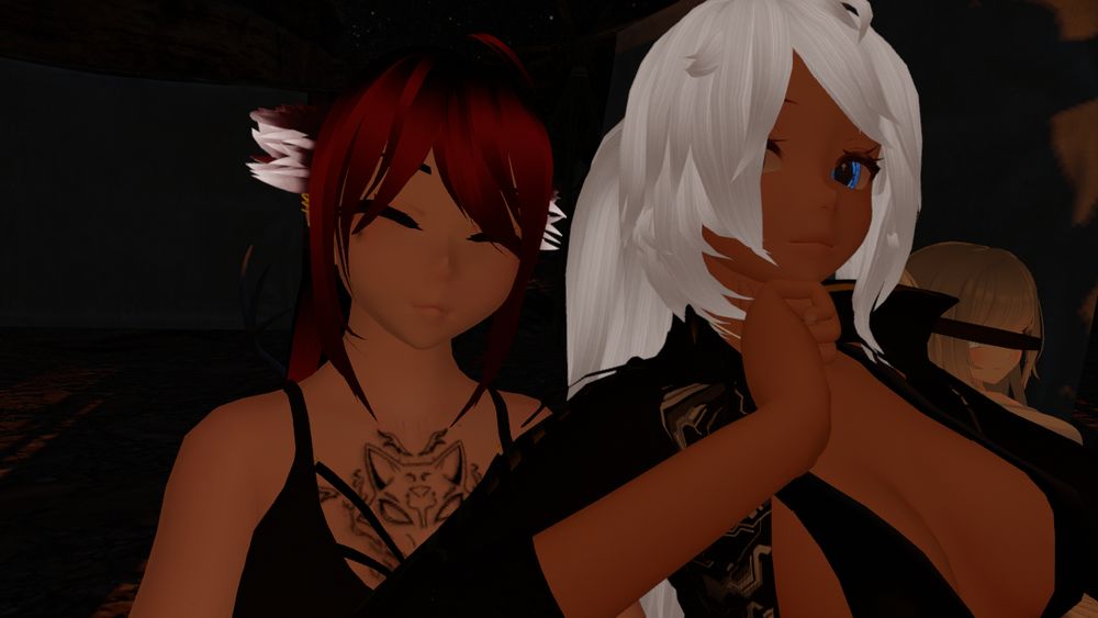 Photo shows the me and Talon-01 in our avatars at a VRChat immersive experience called Shadow Canyon - A Puppeteer's Tale. It is night time and our avatars are covered in a warm glow from a fire. 