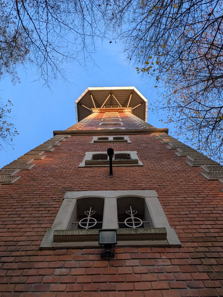 backsteinturm von unten nach oben fotographiert. eine überwachungskamera filmt nach unten