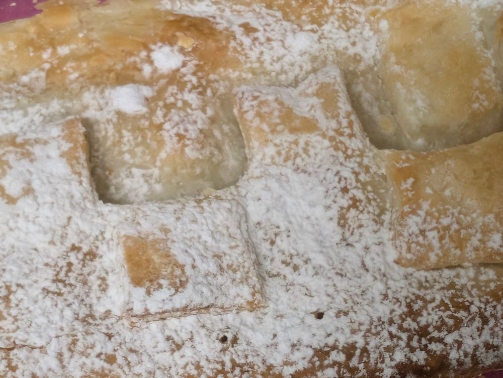 detail apfelschlangerl aus blätterteig mit staubzucker beschneit