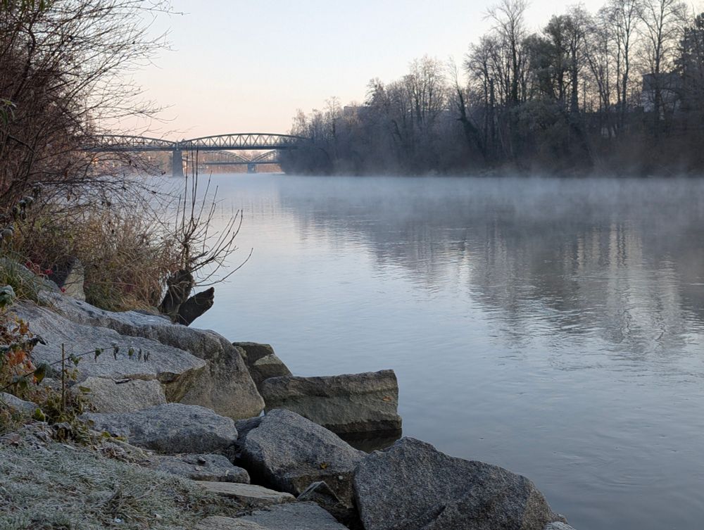 fluss mit nebelschwaden am wasser bei klaren himmel. im hintergrund ist eine fachwerkbrücke erkennbar