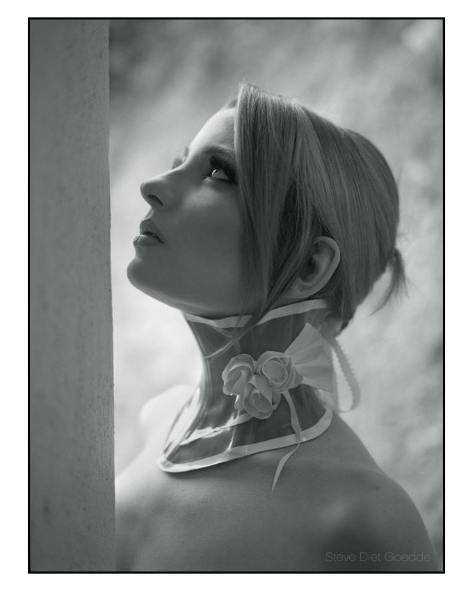 A black and white photograph of a model looking skyward wearing a fanciful neck collar made of latex. #latex #latexfashion #fetish #fetishfashion