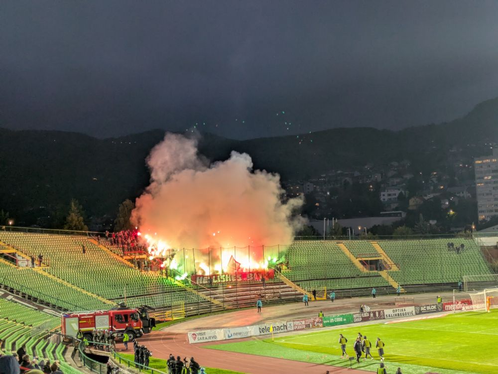 Orange and green flares against the night sky during a bad football game 