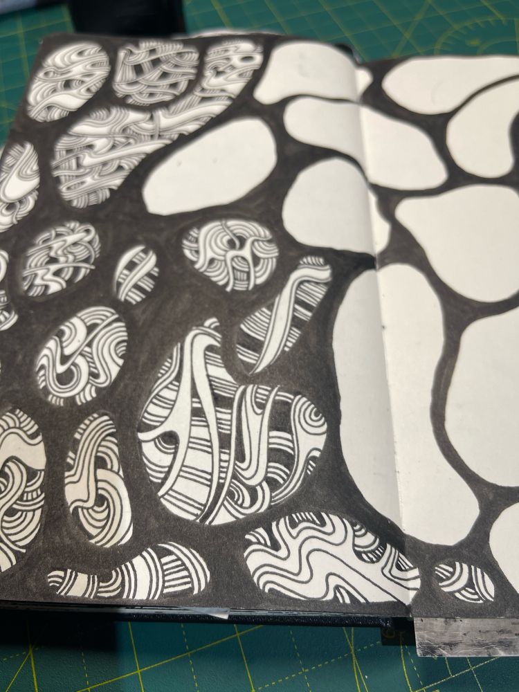 Black and white doodle partly finished. Lots of black brush strokes and squiggly lines 