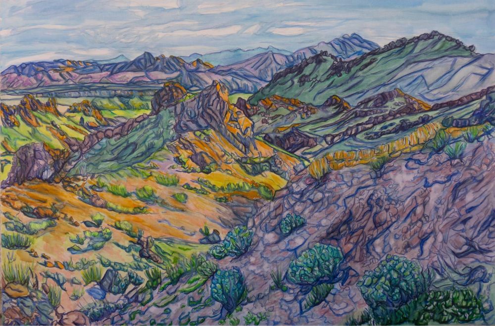 Purple & green rocky hills in the desert at twilight with the orange glow of sunset lighting up the distance and a hill ahead