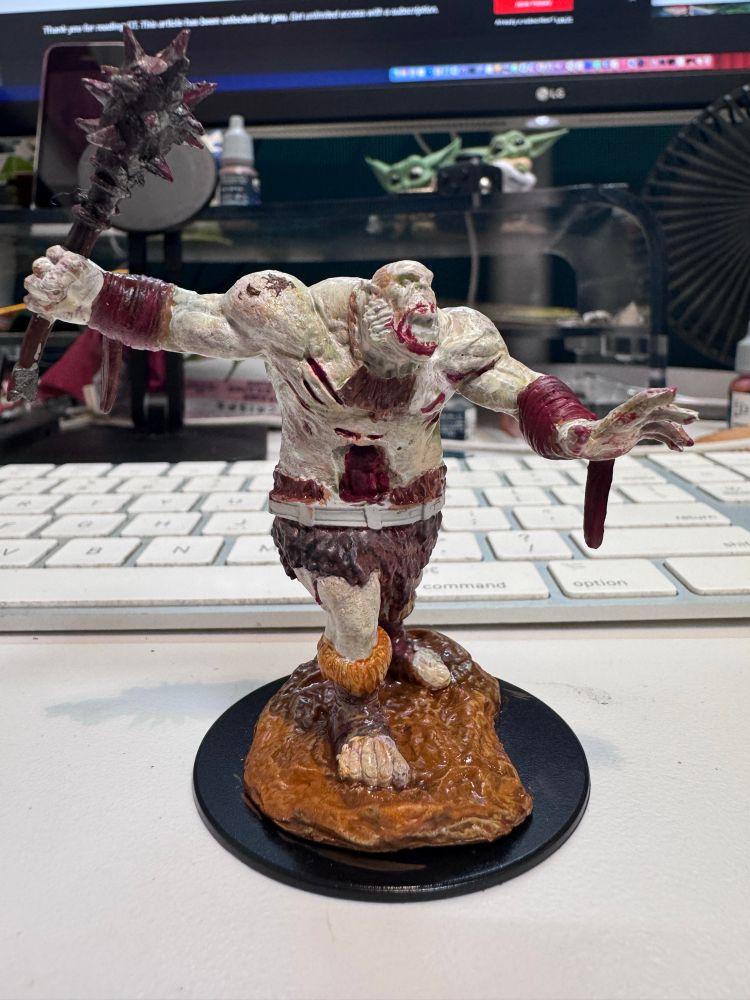 An ogre zombie miniature that’s partially painted. 