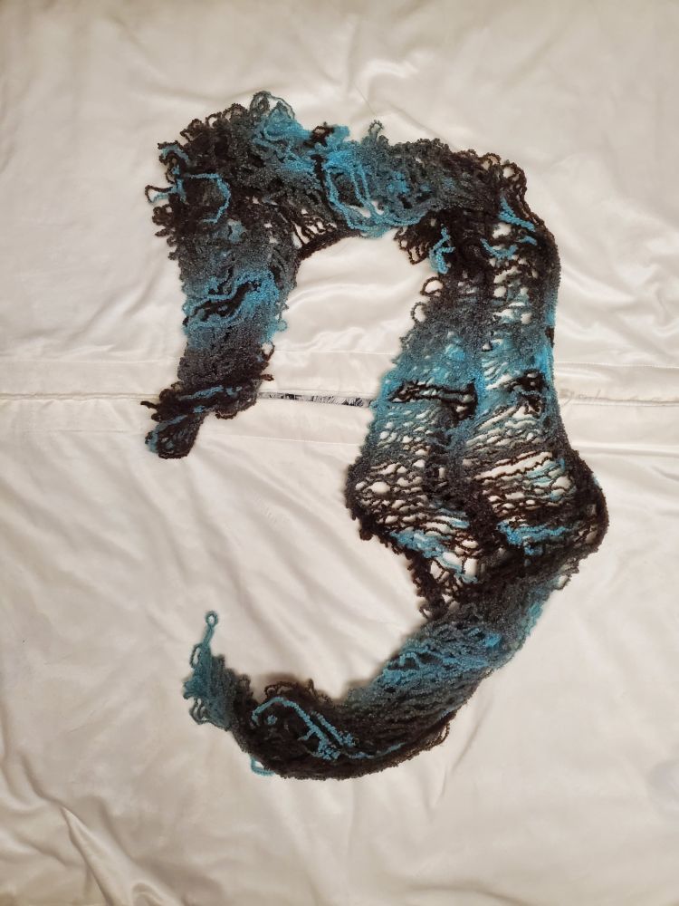 A picture of a brown and blue scarf that seems to be in the shape of a seahorse on a white background. 