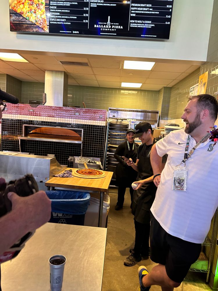 Some fans and pizza makers with a home run ball at the mariners game 